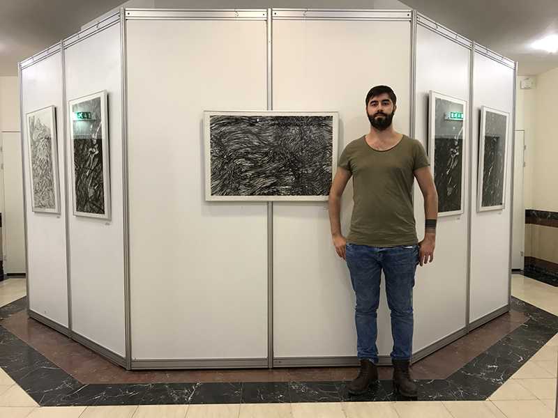 Sergejs Kolecenko standing in front of his works at solo exhibition show in Salekhard, Russia in 2017