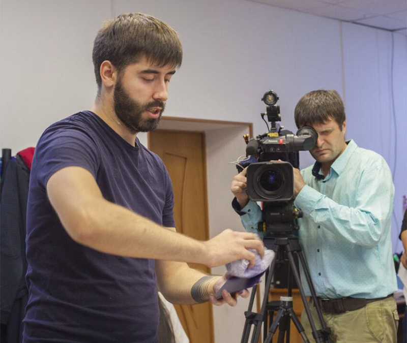 Sergejs Kolecenko showing students mezzotint inking process at workshop and video operator is filming it from behind in Salekhard, Russia 2017